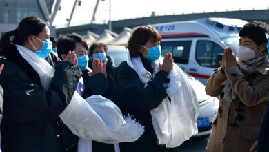 Doctor holding 51 extracted objects from a woman's body, medical team observing in background