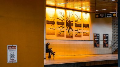 A worried woman sitting on a couch holding her forehead, symbolizing anxiety or stress, in a dimly lit room